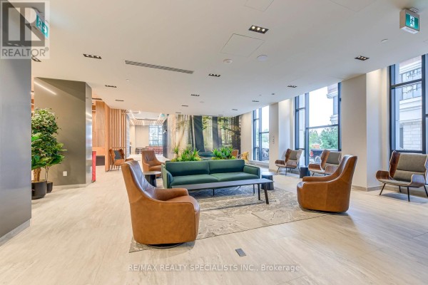 Spacious lobby lounge area with leather armchairs, a green sofa, and a large nature-themed mural. - 1018 - 2485 Eglinton Avenue, Mississauga