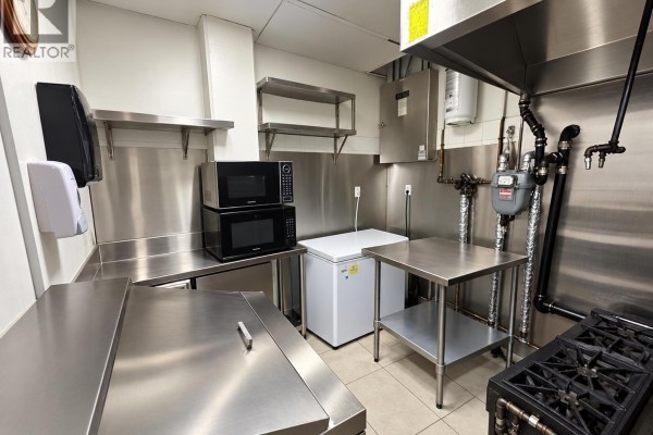 Commercial kitchen with stainless steel counters, microwaves, a freezer, and cooking equipment. - 1018 4500 Kingsway, Burnaby