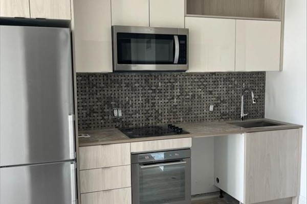 Compact kitchen with stainless steel appliances, grey tiled backsplash, and light wood cabinets. - 1018 Se - 60 Princess Street, Toronto