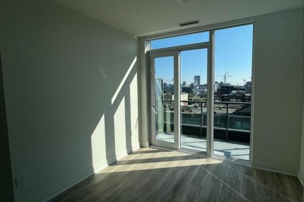 Empty room with light walls, wooden floors, and large sliding glass doors to a balcony. - 1018 Se - 60 Princess Street, Toronto
