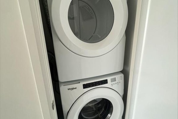 Stacked white Whirlpool washer and dryer units inside a closet with a white door. - 1018 Se - 60 Princess Street, Toronto