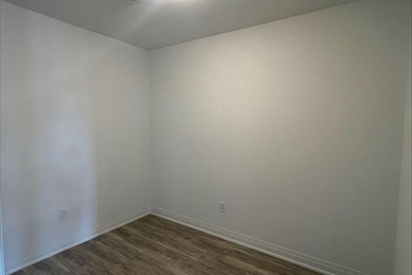 Empty room with white walls and light wood laminate flooring, featuring baseboard trim. - 1018 Se - 60 Princess Street, Toronto