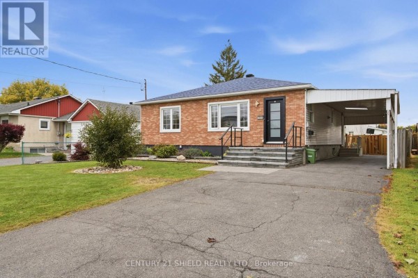Front view of a brick bungalow with a covered carport and lawn. - 1019 Miron Avenue, Cornwall