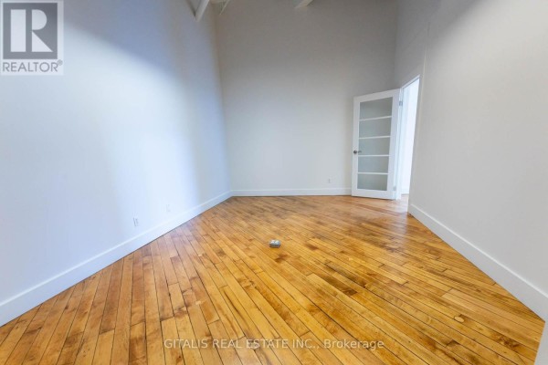 Empty office space with white walls, wood floors, and several desks with dividers. - 101a - 219 Dufferin Street, Toronto