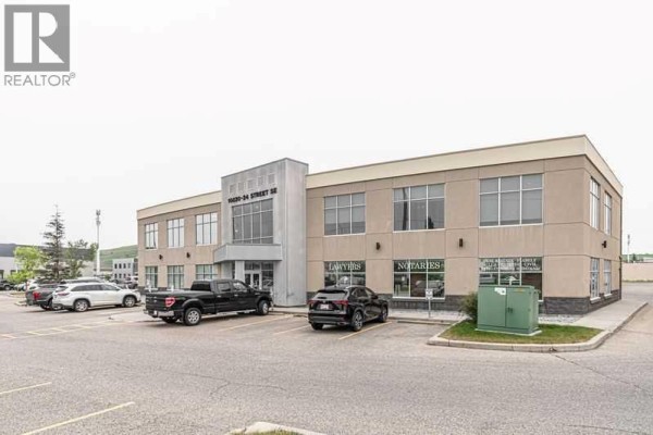 Commercial reception area with light wood desk, brick accent wall, and dark green wall. - 102, 10820 24 Street Se, Calgary