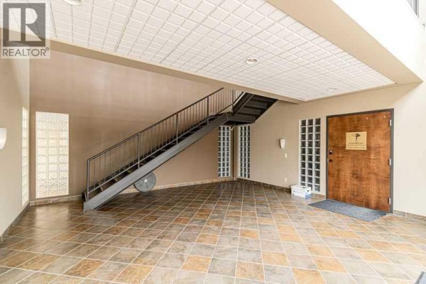 Rear exterior of a commercial building with brick facade and multiple garage bay doors. - 102, 10820 24 Street Se, Calgary