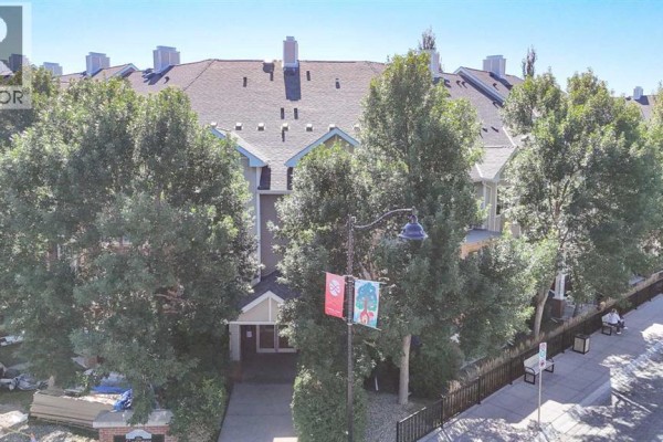 Exterior view of an apartment building entrance with trees and lampposts. - 102, 1811 34 Avenue Sw, Calgary