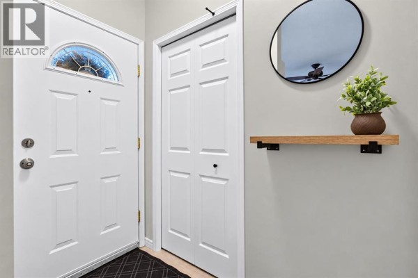 Interior view of a townhouse entrance with a white door and closet. - 102, 622 56 Avenue Sw, Calgary