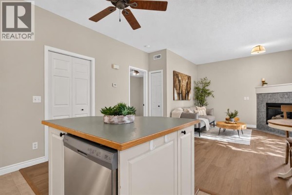 Open concept kitchen and living room with a fireplace and island counter. - 102, 622 56 Avenue Sw, Calgary