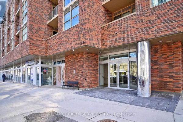 Building entrance with glass doors, silver columns, and brick facade. - 102 - 1787 St. Clair Avenue W, Toronto
