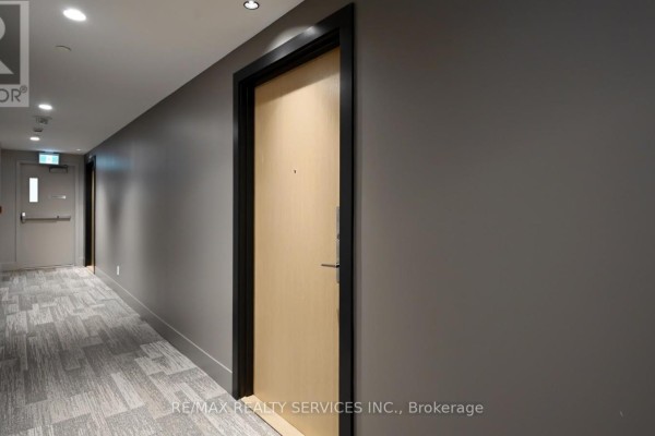 Apartment building hallway with grey walls, carpeted floor, and beige doors. - 102 - 1787 St. Clair Avenue W, Toronto