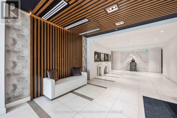 Modern lobby with white tiled floors, a white sofa, and wood slat wall accents. - 102 - 2 Teagarden Court N, Toronto