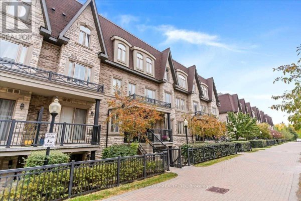 Side view of multi-story brick townhouses with stone detailing and autumn trees. - 102 - 320 John Street, Markham