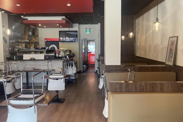 View down the length of a restaurant, showing tables, booths, and service counter. - 102 - 5460 Yonge Street, Toronto