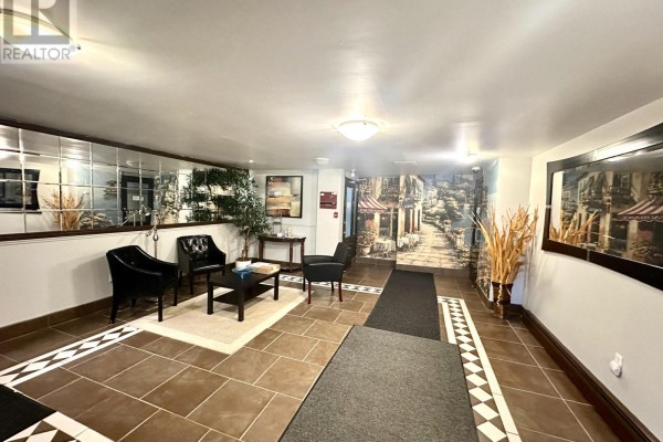 Lobby hallway with tiled floors, mirrored walls, and a European street mural. - 102 - 7 Riverview Boulevard, St  Catharines