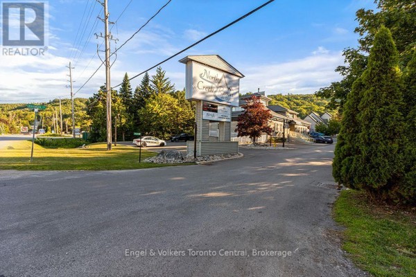 North Creek Resort sign at entrance with trees and a paved road in sunny weather. - 102 - 796468 Grey Road 19 Road, Blue Mountains