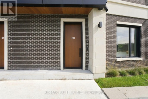 Entrance door labeled H102 with dark brick and beige stone exterior. - 102 - 8 Walder Lane, Richmond Hill