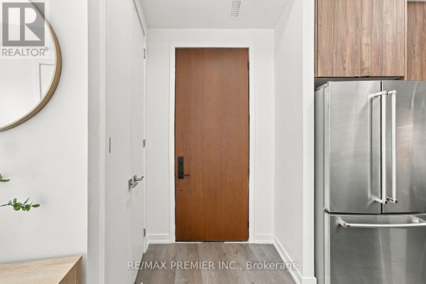 Interior entryway with a wooden door, stainless steel refrigerator, and light wood flooring. - 102 - 8 Walder Lane, Richmond Hill