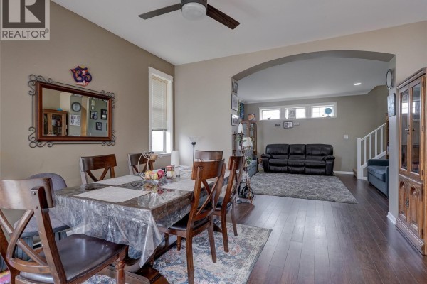 Dining area with a table set for six, dark wood chairs, and an adjacent living room. - 102 2923 Phipps Rd, Langford