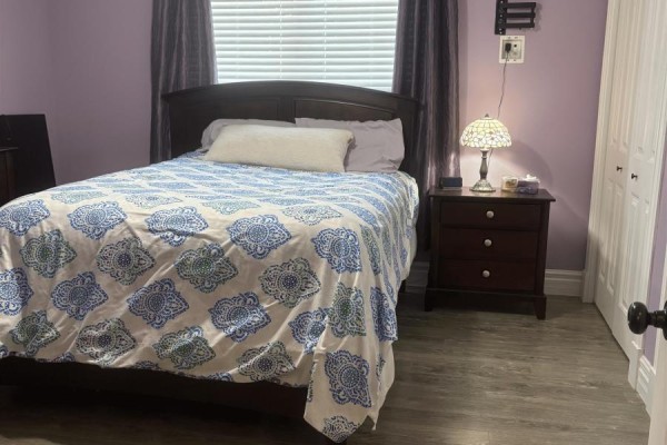 Bedroom with a queen-size bed, patterned duvet, and purple walls. - 36 Ducks Landing Unit 102, Stratford