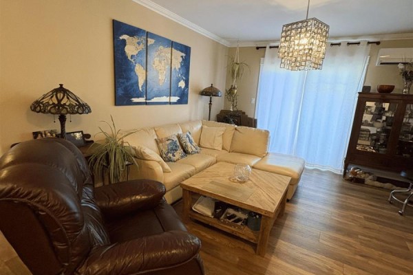 Living room featuring a sectional sofa, leather armchair, coffee table, and a world map artwork. - 36 Ducks Landing Unit 102, Stratford