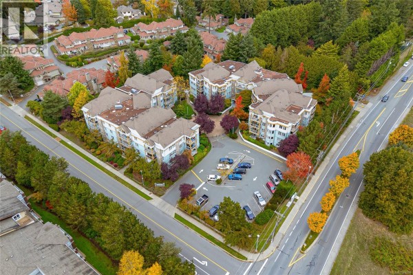 Aerial view of apartment buildings surrounded by trees and roads. - 102 490 Marsett Pl, Saanich