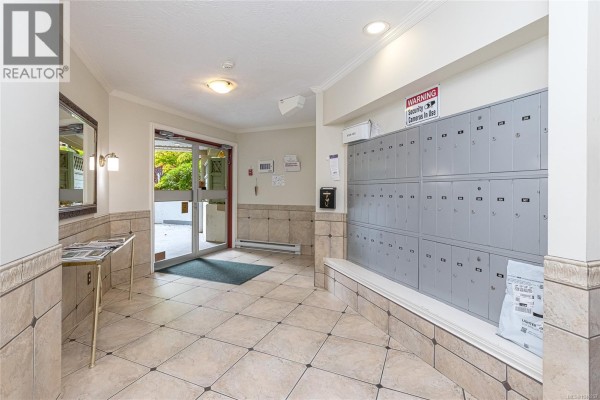 Building lobby with mailboxes and tiled floors. - 102 490 Marsett Pl, Saanich