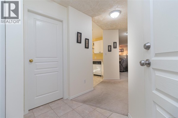 Interior hallway with white doors and access to kitchen and living area. - 102 490 Marsett Pl, Saanich