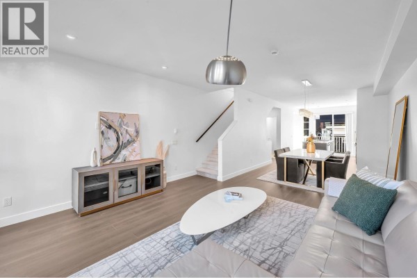 Living area showing sofa, media console, and a view towards the dining area and staircase. - 102 548 Foster Avenue, Coquitlam