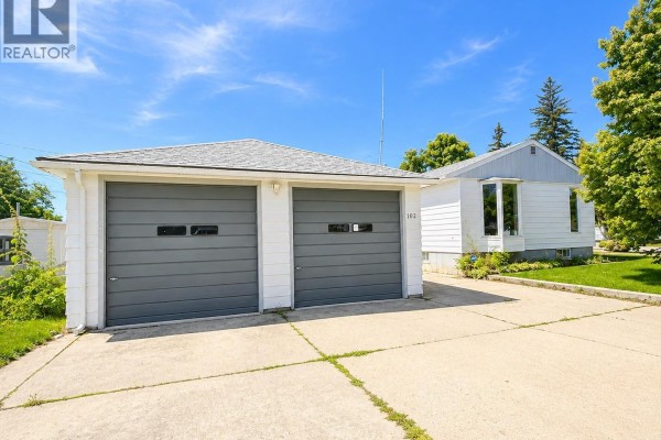 Attached two-car garage with grey doors and a concrete driveway. - 102 6th Avenue W, Eatonia