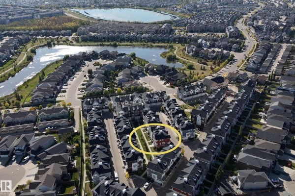 Aerial view of a residential neighborhood with townhouses, roads, and a lake. - #102 903 Crystallina Nera Wy Nw, Edmonton