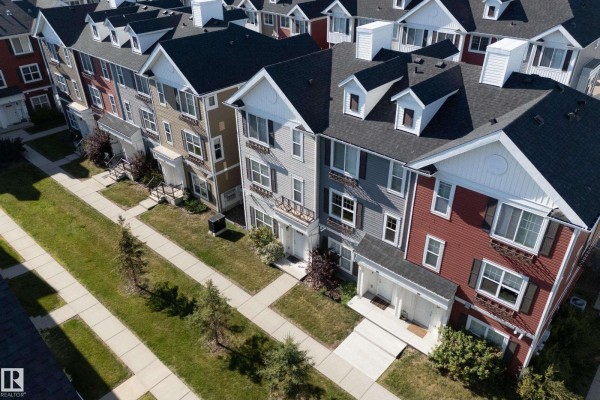 Close-up aerial view of a row of townhouses with grey, beige, and red siding. - #102 903 Crystallina Nera Wy Nw, Edmonton