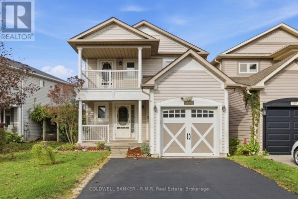 Front view of a beige-sided two-story house with a white-trimmed garage door and a covered front porch. - 102 Boswell Drive, Clarington