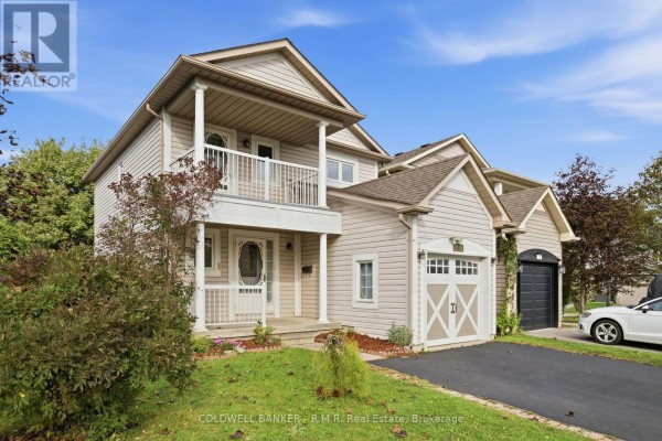 View of the beige-sided exterior of a house with a covered balcony and a detached garage. - 102 Boswell Drive, Clarington