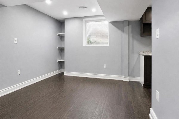 Unfinished basement room with grey walls, dark wood floor, a small window, and shelves. - 102 Earlsbridge Boulevard, Brampton