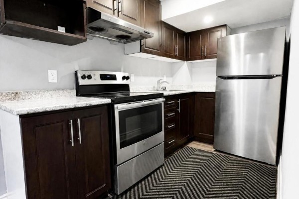 Small basement kitchen with dark wood cabinets, stainless steel appliances, and granite countertops. - 102 Earlsbridge Boulevard, Brampton