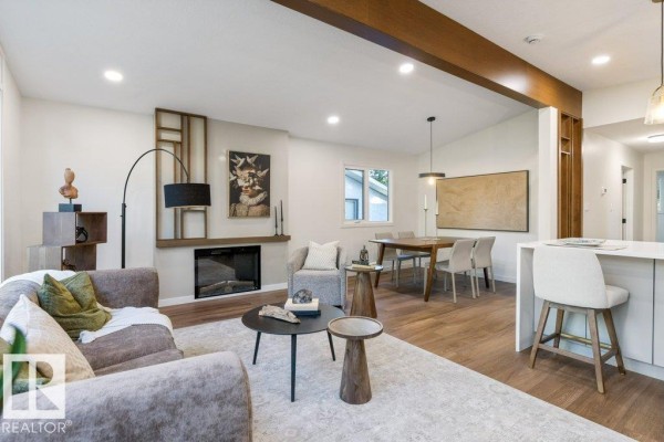 Living room and dining area with fireplace, sofa, dining table, and kitchen island. - 102 Goodridge Dr, St  Albert