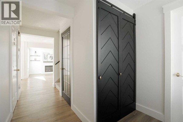 Hallway with light wood flooring and black chevron barn doors. - 102 Goodwin Place, Fort Mcmurray