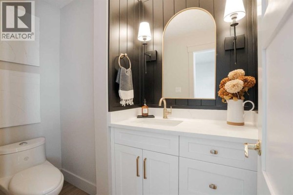 Powder room with a white vanity, gold fixtures, and a black shiplap accent wall. - 102 Goodwin Place, Fort Mcmurray