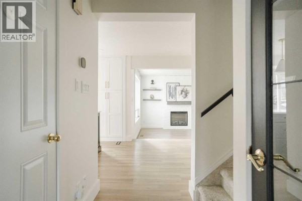 View from the entrance into a living room with a fireplace and white cabinetry. - 102 Goodwin Place, Fort Mcmurray