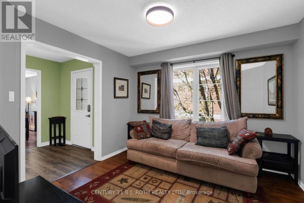 Living room with a sofa, decorative mirrors, and a window overlooking the exterior. - 102 Holgate Street, Barrie