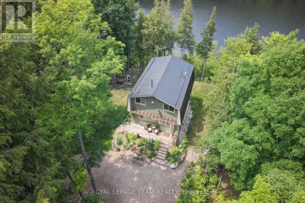 Aerial view of a green house nestled among dense trees with a lake in the background. - 102 Mcvicar Lane, Mcnab/braeside