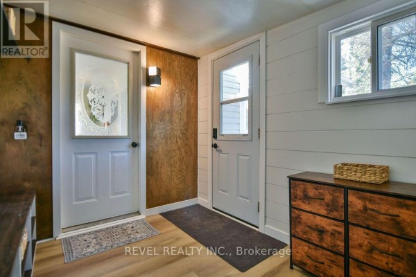 Interior hallway with two doors, wood paneling, and modern dresser. - 102 Notre Dame Place, Timmins