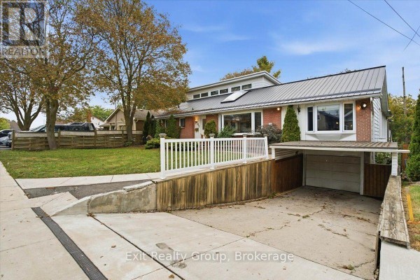Driveway leading to a carport and garage attached to the side of a brick house. - 102 Orchard Drive, Belleville