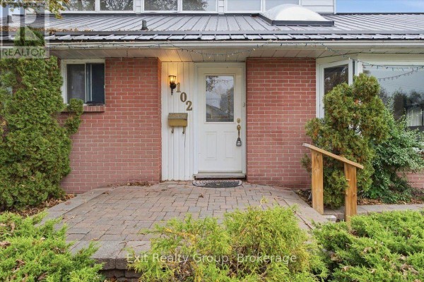 Close-up of the front entrance with a red brick facade, white door, and number 102. - 102 Orchard Drive, Belleville