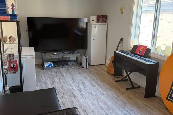 Living area with large TV, gaming consoles, digital piano, and guitar. - 102 Parkdale Avenue N, Hamilton