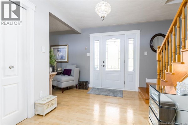 Interior foyer with light hardwood floors, white double doors, gray walls, and a wooden staircase. - 102 Plaisante Street, Drummond