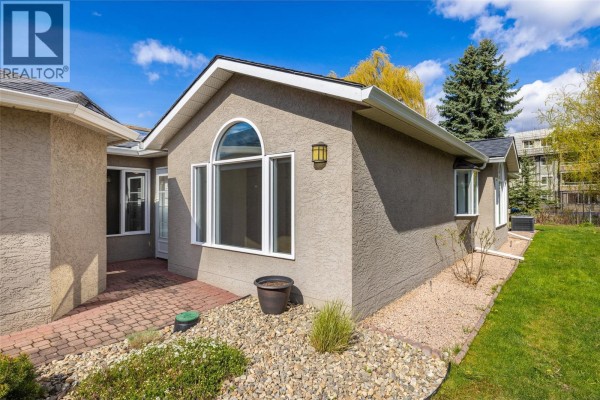 Corner view of the townhouse highlighting a large arched window and side yard with landscaping. - 1020 Lanfranco Road Unit# 28, Kelowna