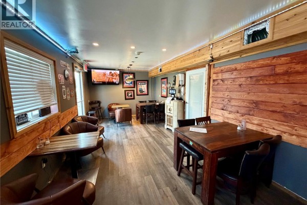 Interior view showing dining tables, leather chairs, and a wood-paneled wall. - 1020 Railway Avenue, Carnduff