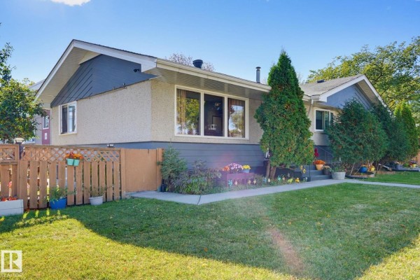 Side view of a duplex showing the light beige stucco exterior and grey lower siding. - 10207 & 10209 120 Av Nw, Edmonton
